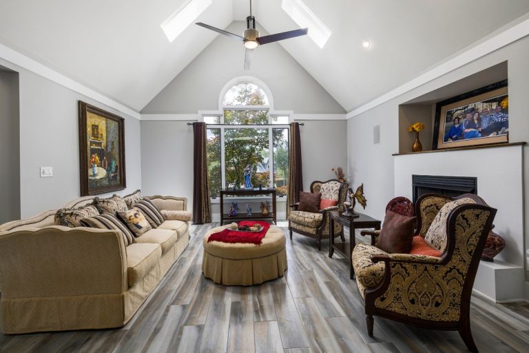 A spacious living room featuring a vaulted ceiling, hardwood floors, and stylish furniture, showcasing a modern design.