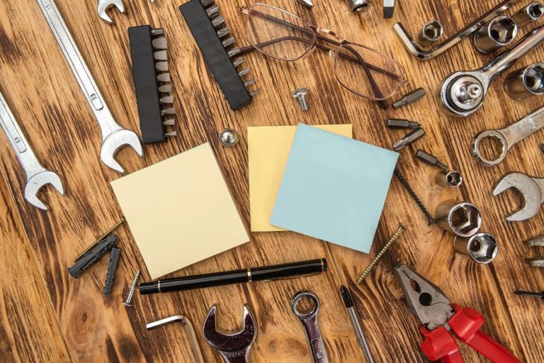 1. A wooden table displaying various tools, including wrenches, alongside a notepad for notes or measurements.